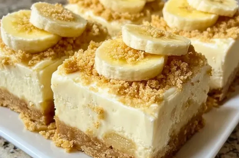 Delicious banana pudding cheesecake squares topped with whipped cream and banana slices.