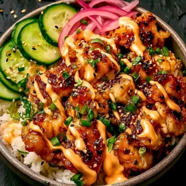 Crispy chicken drizzled with creamy spicy sauce on a plate