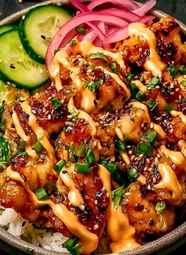 Crispy chicken drizzled with creamy spicy sauce on a plate