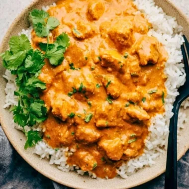 Delicious Crockpot Butter Chicken served with rice and garnished with cilantro.