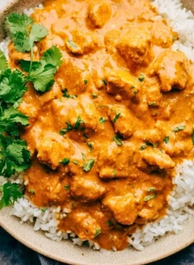 Delicious Crockpot Butter Chicken served with rice and garnished with cilantro.
