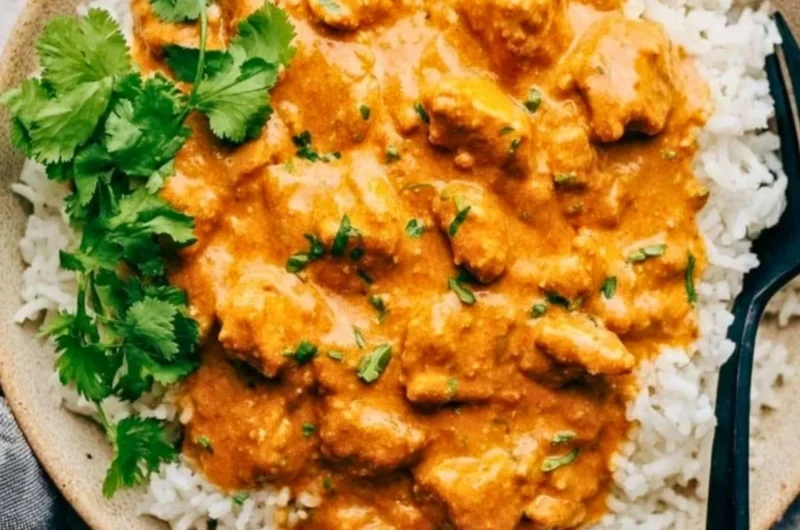 Delicious Crockpot Butter Chicken served with rice and garnished with cilantro.