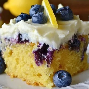 Cozy lemon blueberry poke cake topped with fresh blueberries and lemon glaze