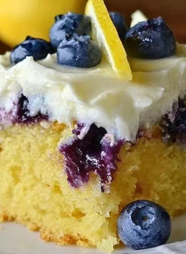 Cozy lemon blueberry poke cake topped with fresh blueberries and lemon glaze