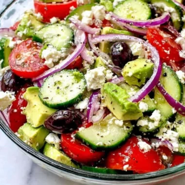 Greek salad with avocado, feta cheese, and fresh vegetables in a bowl