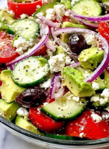 Greek salad with avocado, feta cheese, and fresh vegetables in a bowl