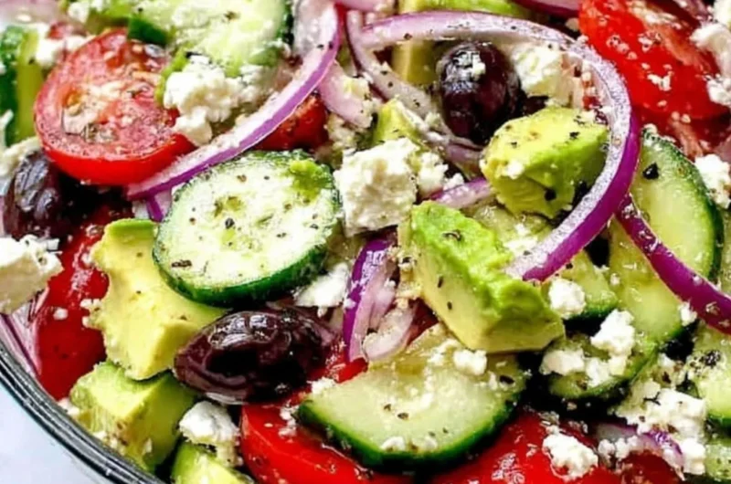 Greek salad with avocado, feta cheese, and fresh vegetables in a bowl