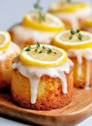 Mini lemon drizzle cakes topped with glaze and lemon zest.