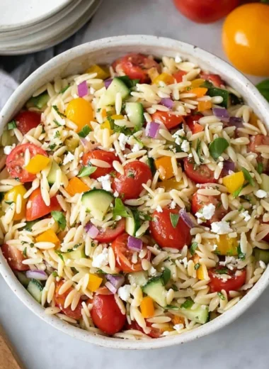 Colorful orzo salad with vegetables and dressing in a bowl