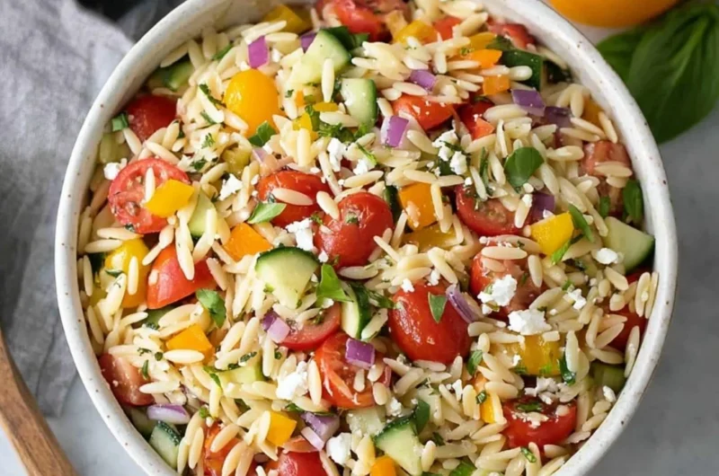 Colorful orzo salad with vegetables and dressing in a bowl