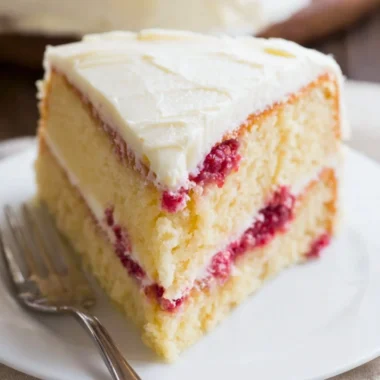 Sliced Raspberry Lemon Cake on a decorative plate with fresh berries