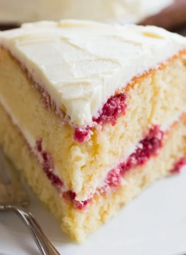 Sliced Raspberry Lemon Cake on a decorative plate with fresh berries