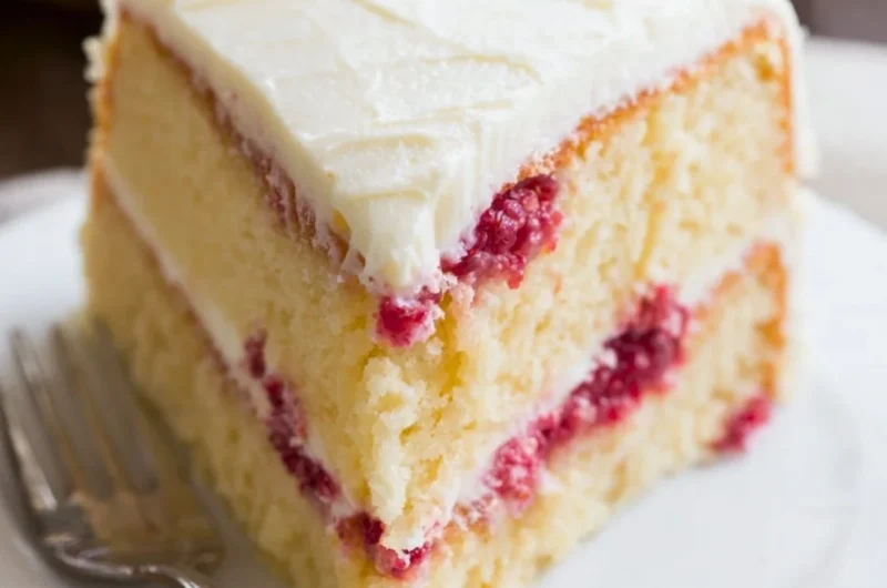 Sliced Raspberry Lemon Cake on a decorative plate with fresh berries