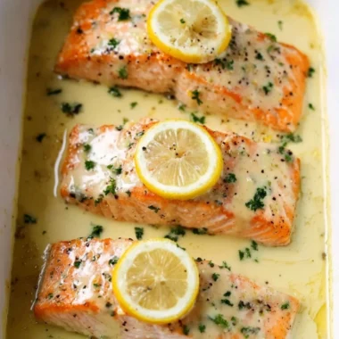 Salmon fillet topped with creamy lemon sauce garnished with herbs.
