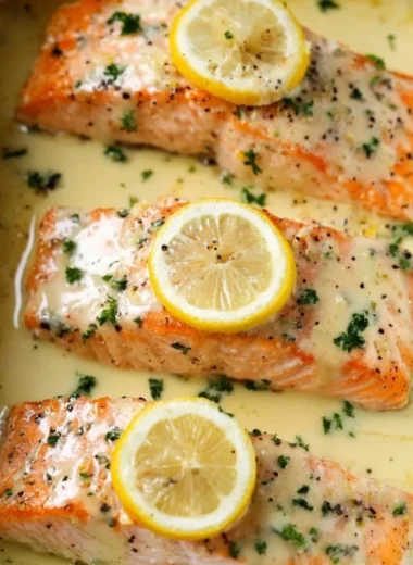 Salmon fillet topped with creamy lemon sauce garnished with herbs.