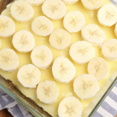 Delicious slice of Banana Pudding Poke Cake topped with whipped cream and banana slices.