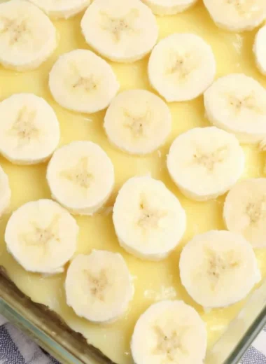 Delicious slice of Banana Pudding Poke Cake topped with whipped cream and banana slices.