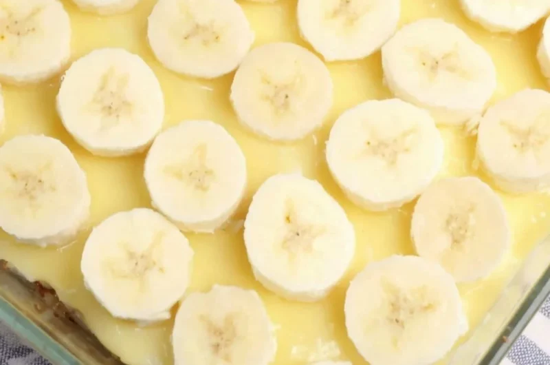 Delicious slice of Banana Pudding Poke Cake topped with whipped cream and banana slices.