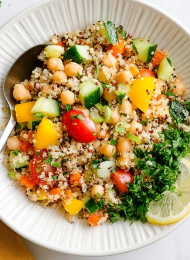 Bowl of Lemon Quinoa Salad with chickpeas, fresh herbs, and lemon wedges