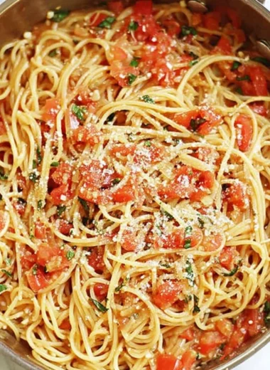 A colorful bowl of one-pot pasta with fresh vegetables and herbs.