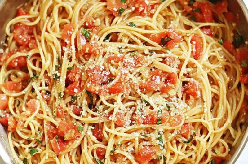 A colorful bowl of one-pot pasta with fresh vegetables and herbs.