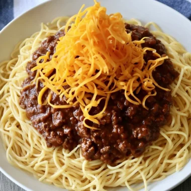 Bowl of cozy Cincinnati chili topped with cheese and onions for a comforting meal.