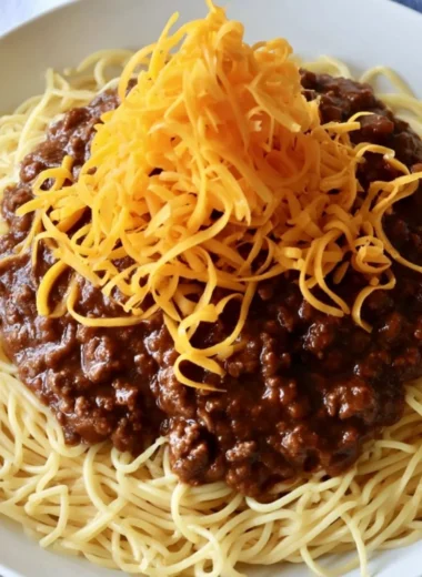 Bowl of cozy Cincinnati chili topped with cheese and onions for a comforting meal.