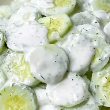 Creamy cucumber salad served in a bowl, garnished with herbs and spices.