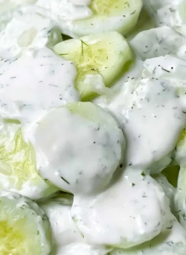 Creamy cucumber salad served in a bowl, garnished with herbs and spices.