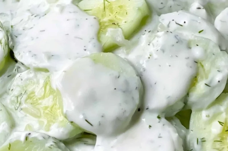 Creamy cucumber salad served in a bowl, garnished with herbs and spices.