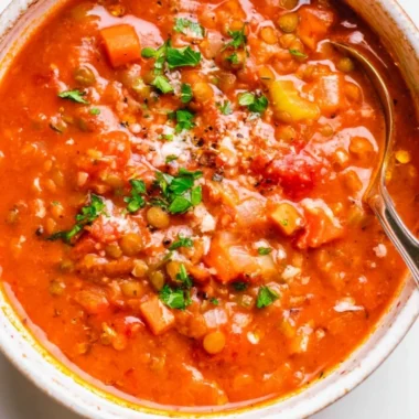 A bowl of Mediterranean Lentil Soup garnished with fresh herbs and olive oil.