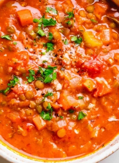 A bowl of Mediterranean Lentil Soup garnished with fresh herbs and olive oil.