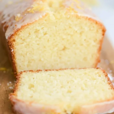 A slice of sourdough discard lemon cake on a white plate with lemon slices