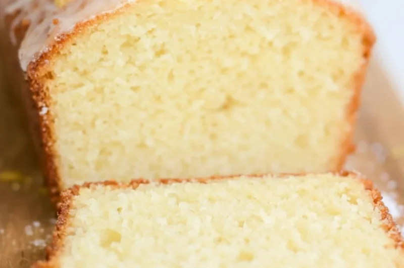 A slice of sourdough discard lemon cake on a white plate with lemon slices